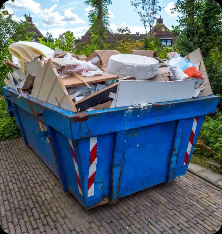 Blue builders skip full of construction debris on a brick path