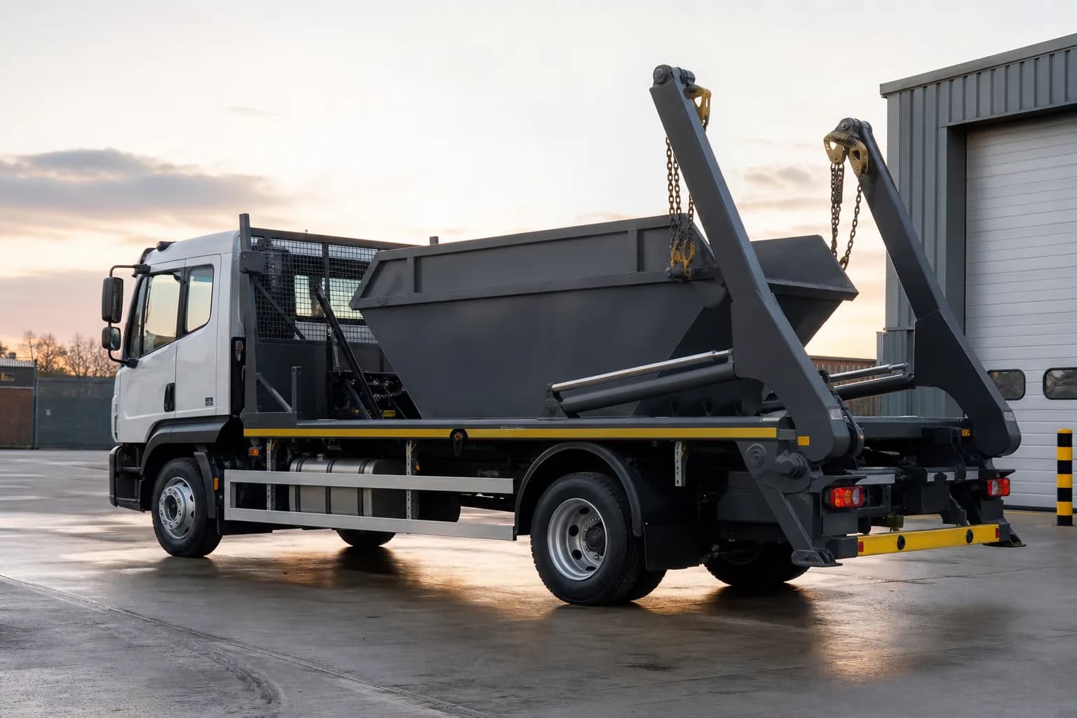 A skip lorry carrying an empty steel skip at the UK Skip Hire depot