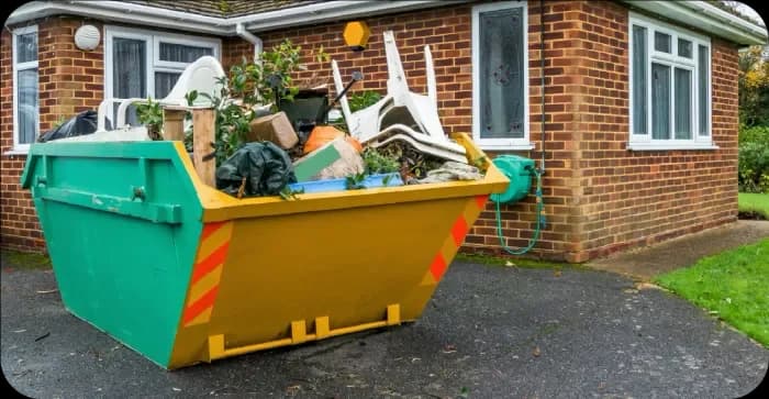 Small skip loaded with household and garden waste outside a home